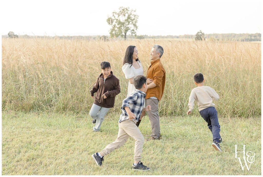 Family enjoying playful moments together in an open field at sunset