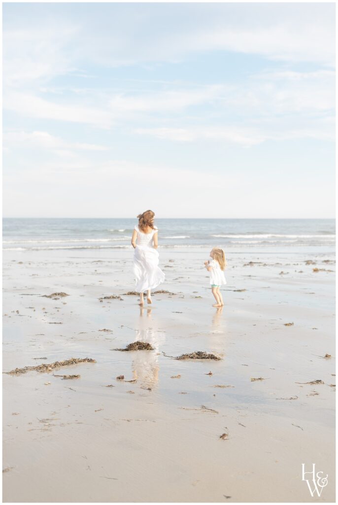 Mom and daughter walking along the shoreline at Wells beach in Maine during family photos