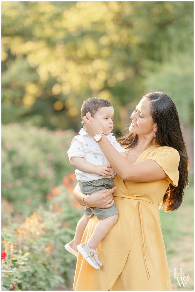 Mom holding her toddler in a sunlit garden during a family photograph