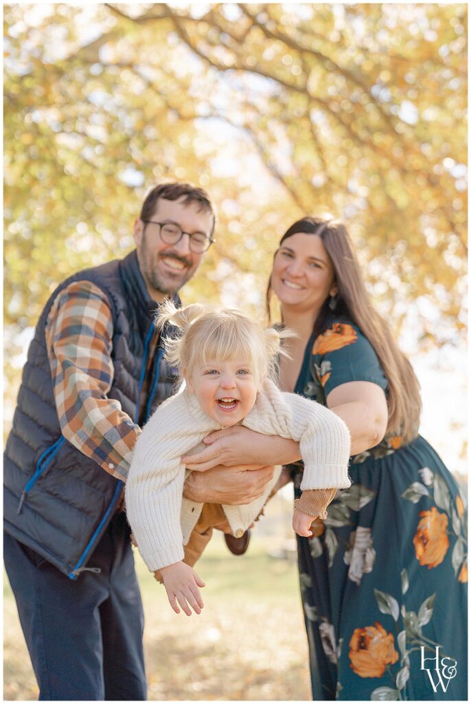 Parents holding their smiling toddler during fall family photos