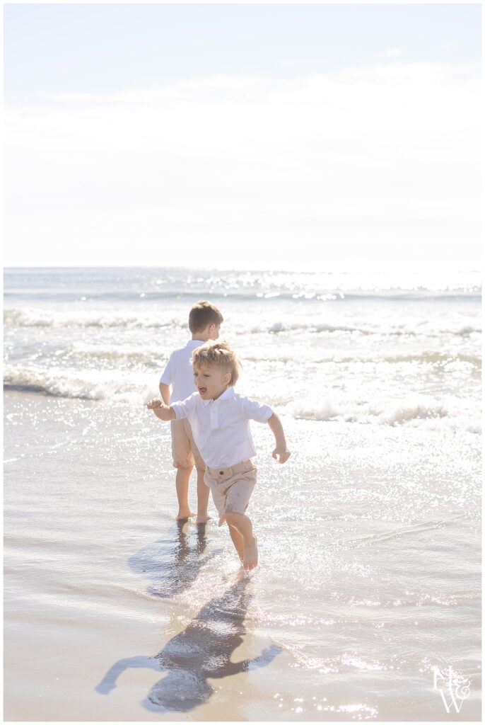 Siblings running through the waves at the beach